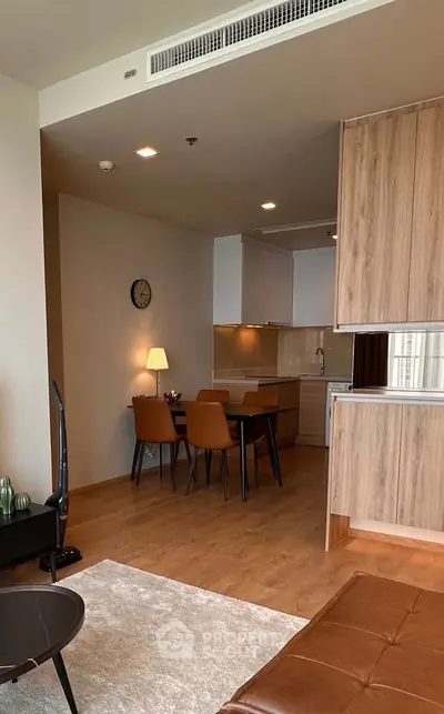 Modern open-plan living and dining area with stylish furniture and wooden flooring in a contemporary apartment.