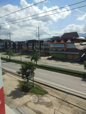 Scenic view of a suburban street with commercial buildings and clear blue sky.