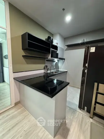 Modern kitchen with sleek black countertops and open shelving, perfect for contemporary living.