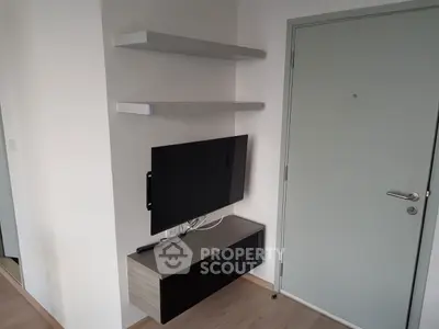 Modern minimalist living room corner with wall-mounted TV and sleek storage unit.