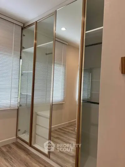 Modern bedroom with mirrored sliding closet doors and wooden flooring