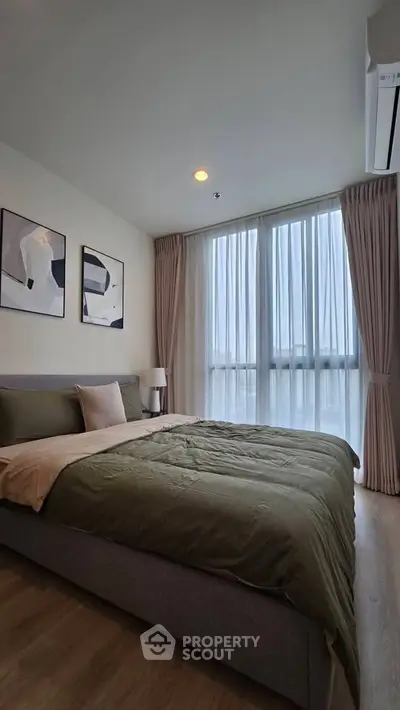 Modern bedroom with large windows and stylish decor in a contemporary apartment.