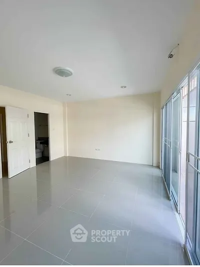 Spacious empty room with large windows and tiled floor, ready for customization.