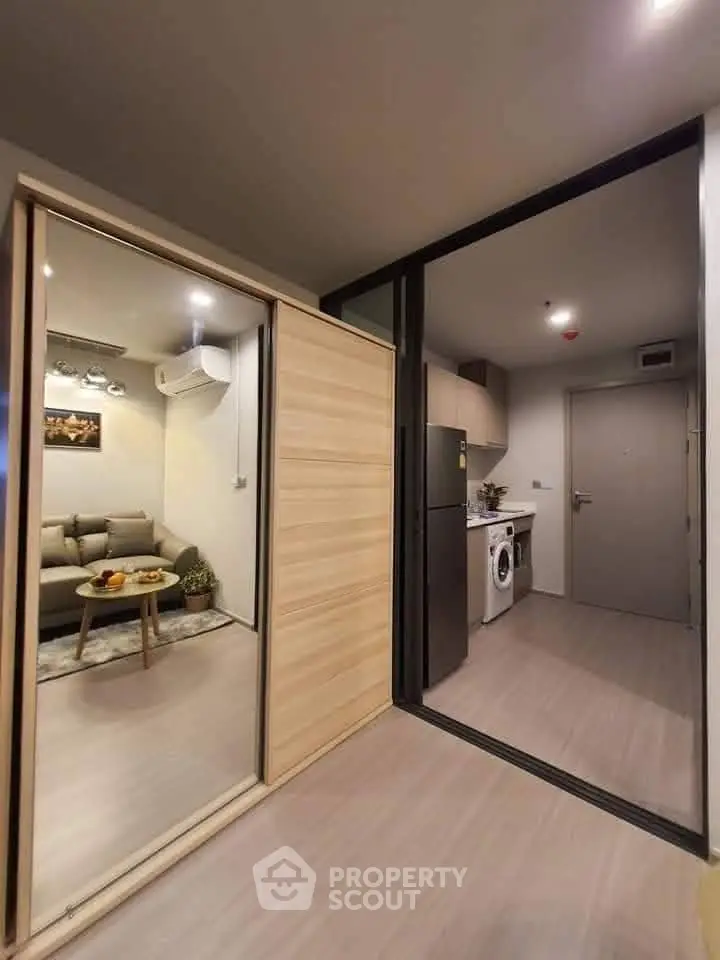 Modern apartment interior with cozy living room and kitchen featuring washing machine and fridge.