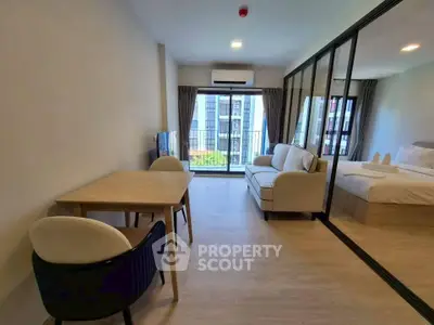 Modern studio apartment with open layout, featuring a cozy living area and large windows for natural light.