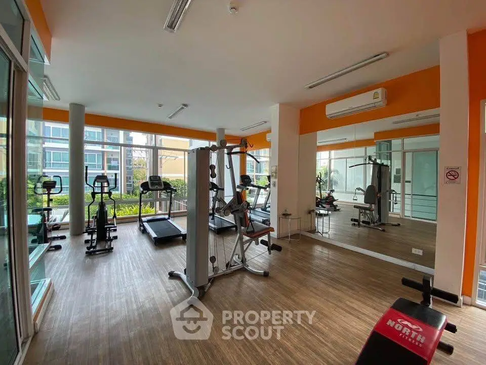 Modern gym with fitness equipment and large mirrors in a bright, spacious room.