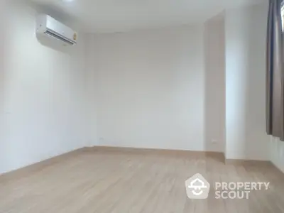 Spacious empty room with wooden flooring and air conditioning unit