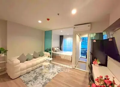 Modern open-plan living room with cozy seating and a view into a stylish bedroom.