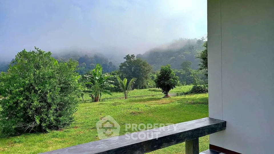 Stunning view from a balcony overlooking lush greenery and misty hills.