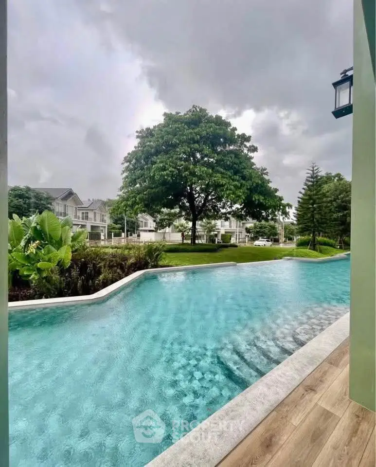 Luxurious residential pool with lush greenery and modern homes in the background.