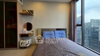 Modern bedroom with large windows offering city views, featuring stylish decor and comfortable bedding.