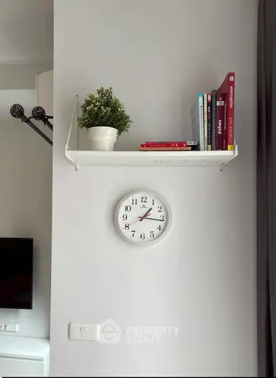 Modern interior with wall-mounted shelf, clock, and decor elements in a stylish living space.