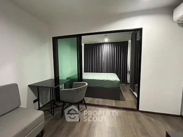 Modern studio apartment with glass partition and sleek furnishings.