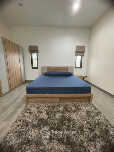 Spacious bedroom with modern wooden furniture and cozy rug