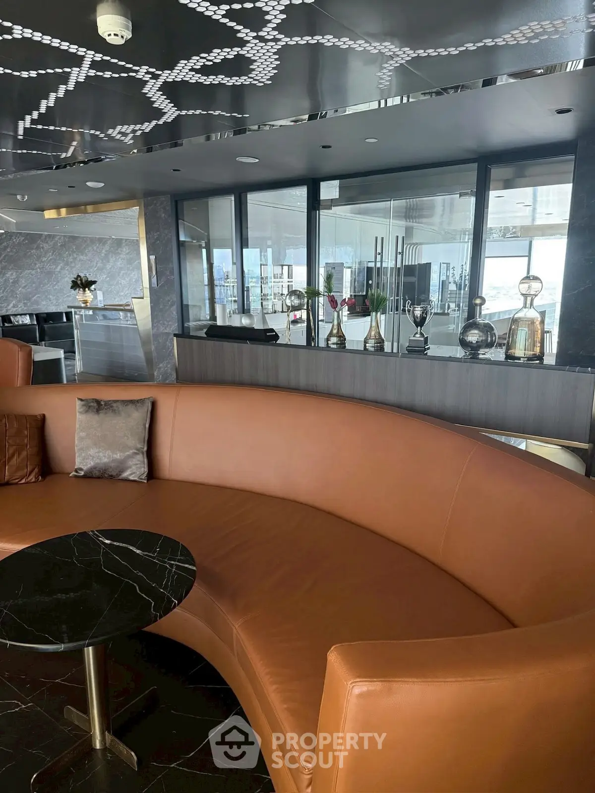 Luxurious modern lounge with curved leather sofa and trophy display, perfect for relaxation and entertainment.