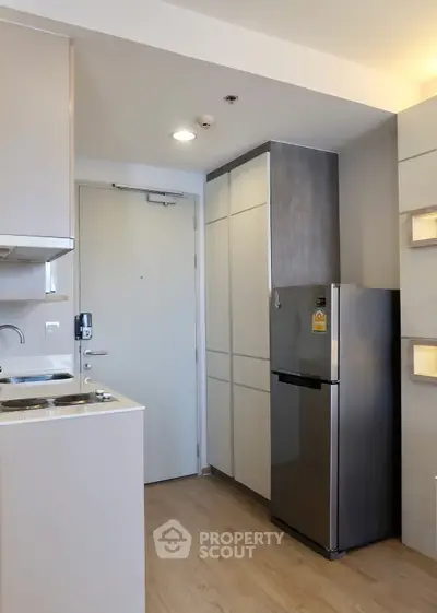 Modern compact kitchen with sleek appliances and stylish cabinetry in a contemporary apartment.