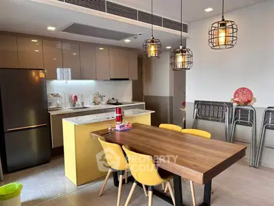 Modern kitchen with dining area, featuring stylish lighting and sleek cabinetry, perfect for family gatherings.
