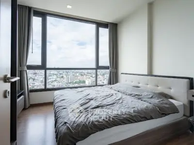Spacious bedroom with large window offering stunning city views in modern apartment.