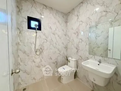 Modern bathroom with marble walls, sleek fixtures, and a minimalist design.
