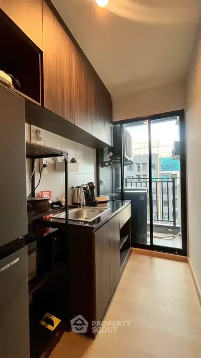 Modern compact kitchen with balcony view in urban apartment