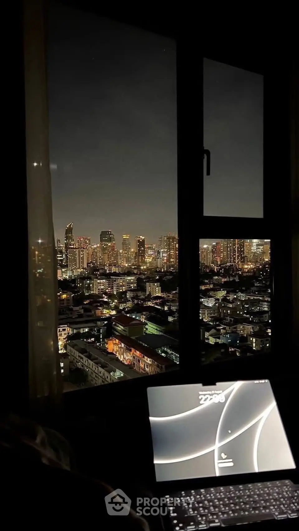 Stunning city skyline view from a high-rise apartment window at night, showcasing vibrant urban lights.