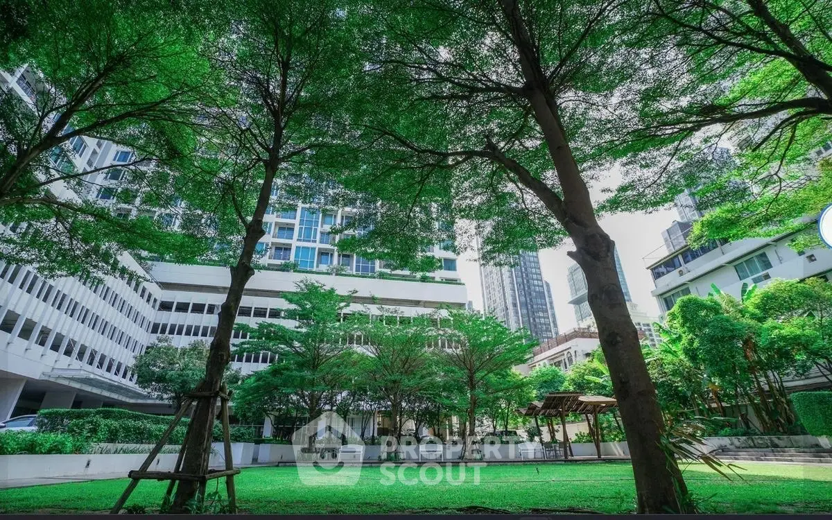 Lush green garden area surrounded by modern high-rise buildings, perfect for relaxation and outdoor activities.