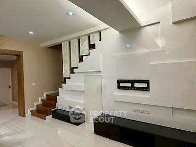 Modern interior with sleek staircase and wall-mounted TV setup in stylish living room.