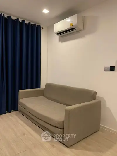 Cozy living room with modern sofa and air conditioning, perfect for relaxation.