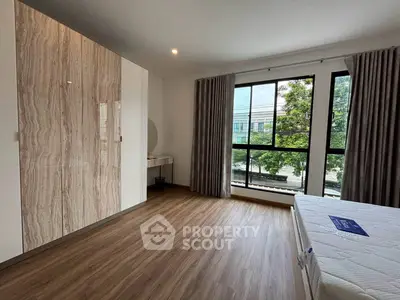 Spacious bedroom with large window and modern wardrobe in a stylish apartment.
