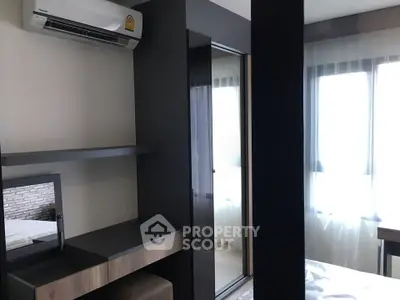 Modern bedroom with air conditioning and natural light through large windows.