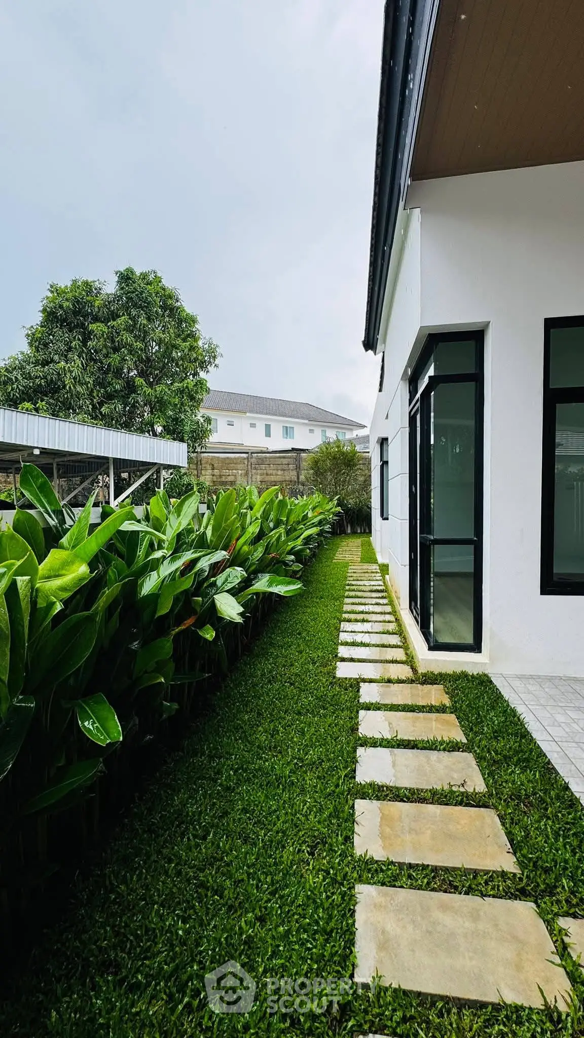 Charming modern home with lush garden and stone pathway, perfect for nature lovers seeking tranquility.