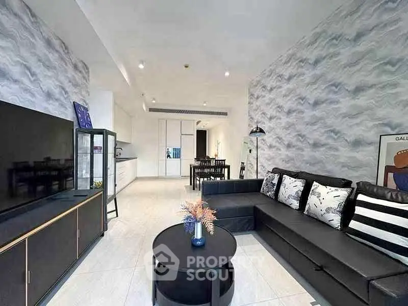Modern living room with stylish decor and open layout, featuring a sleek black sofa and contemporary furnishings.