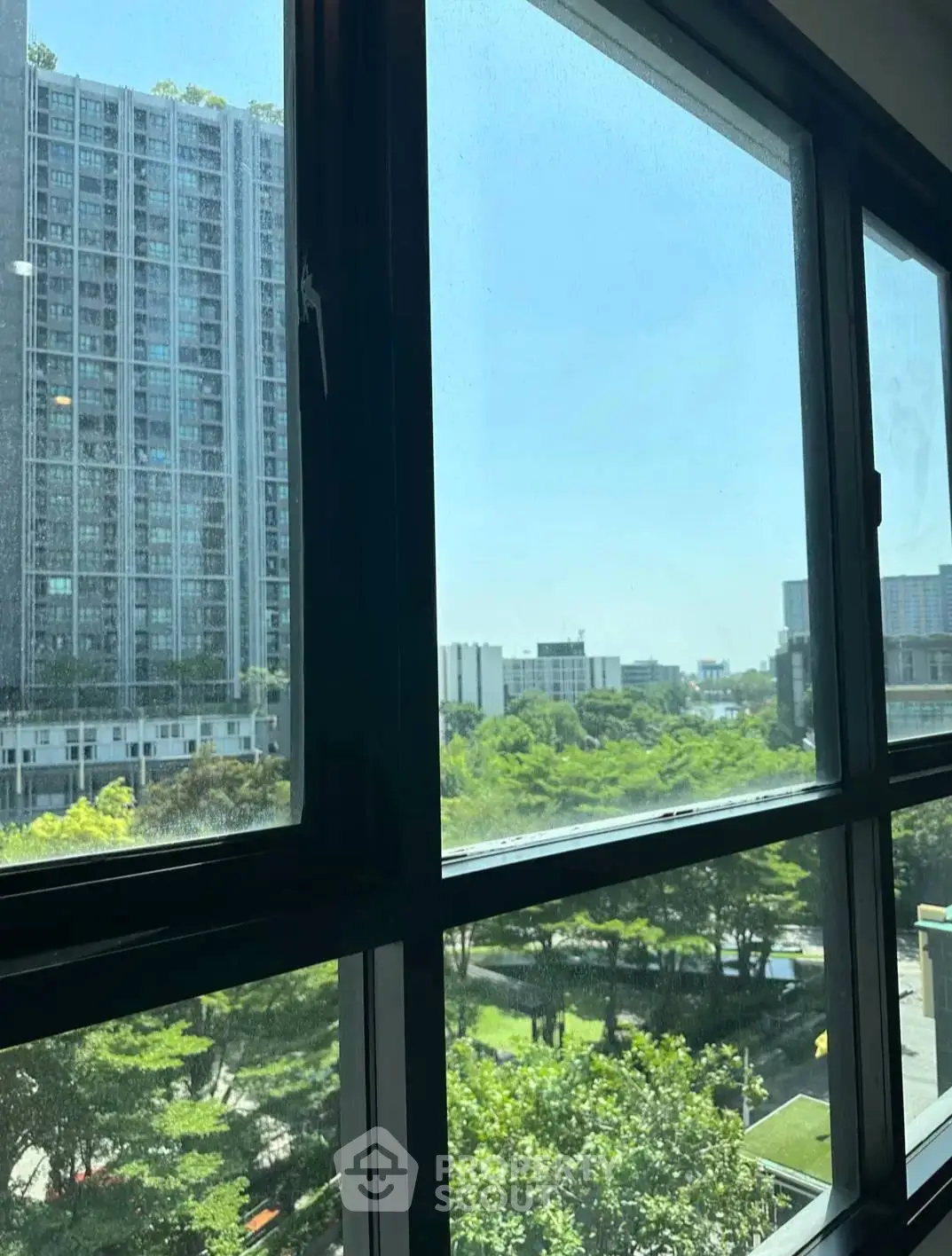 Stunning cityscape view from modern apartment window with lush greenery