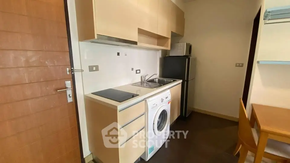 Compact kitchen with washing machine and modern appliances in cozy apartment.