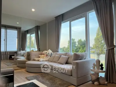 Spacious living room with plush sofa and large windows offering serene views