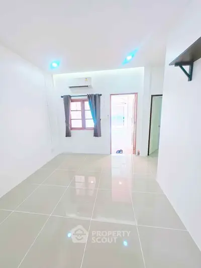 Bright and spacious room with glossy tiled flooring and modern lighting, perfect for versatile living arrangements.