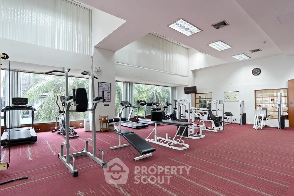 Spacious gym with modern equipment and large windows offering a refreshing view.