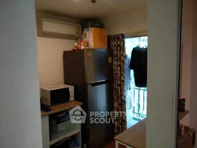Compact kitchen with fridge, microwave, and balcony access in cozy apartment.