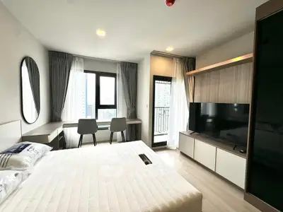 Modern bedroom with balcony and city view, featuring stylish furniture and ample natural light.