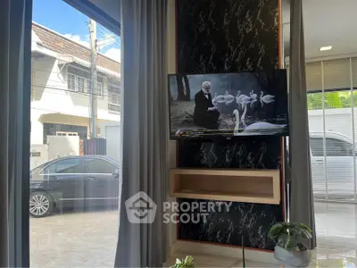 Modern living room with large window, wall-mounted TV, and stylish decor