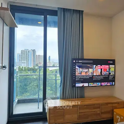 Modern living room with balcony view and wall-mounted TV in urban apartment.