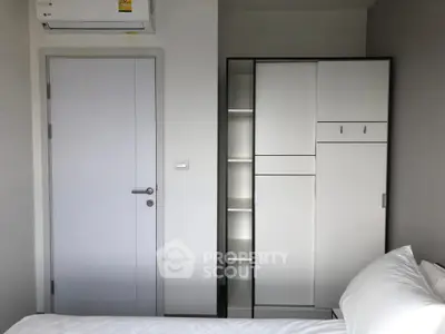 Modern bedroom with sleek wardrobe and air conditioning unit, perfect for comfortable living.