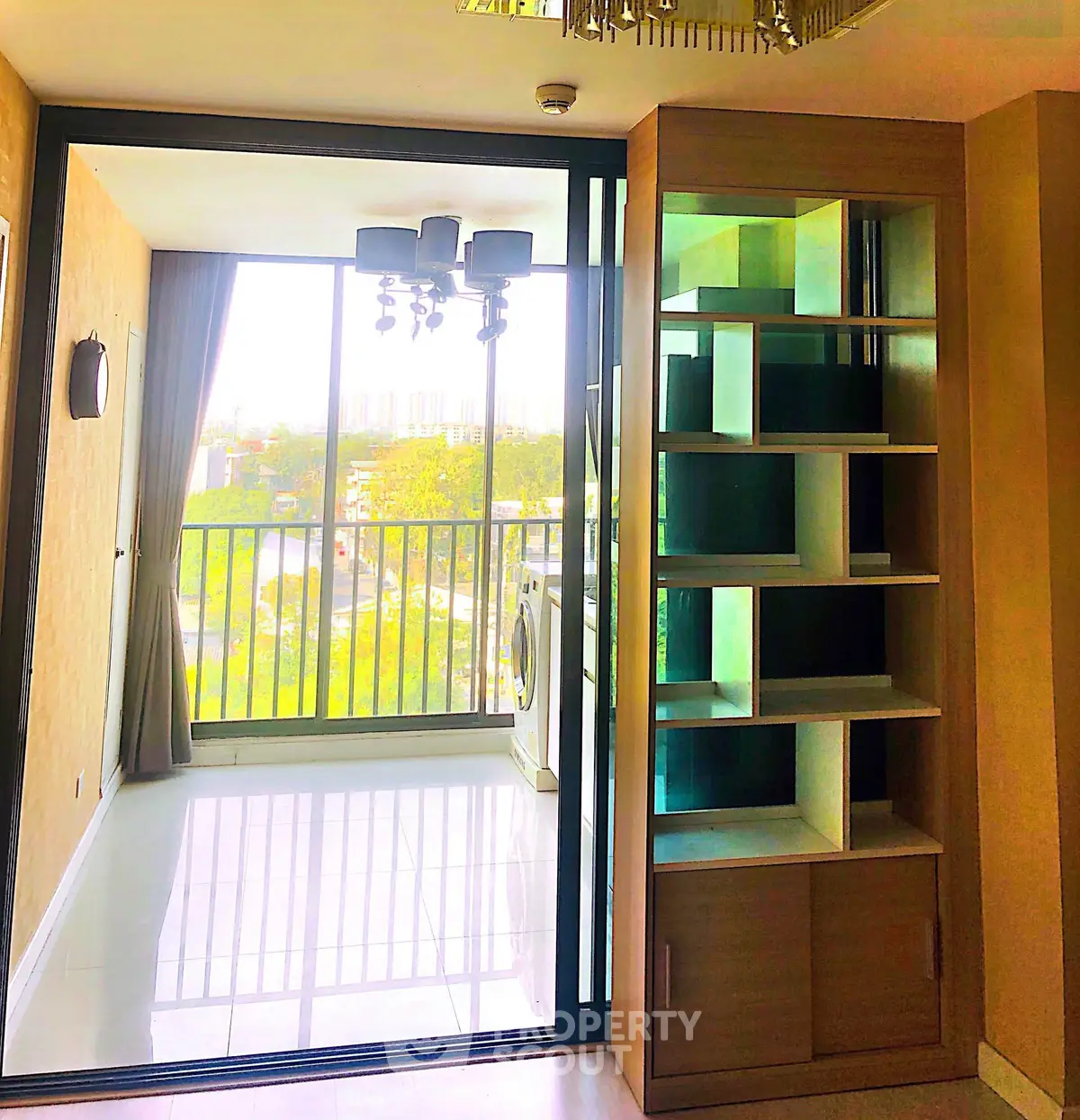 Modern apartment with balcony and built-in shelving, featuring a washing machine and large windows.