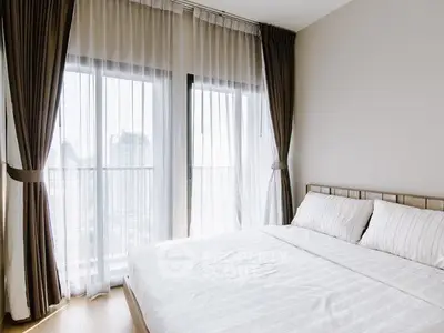 Bright and airy bedroom with floor-to-ceiling windows and elegant curtains.