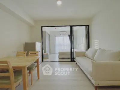 Modern apartment with open living room and dining area, featuring a cozy sofa and wooden dining set.