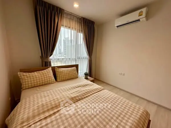 Cozy bedroom with city view and air conditioning in modern apartment.