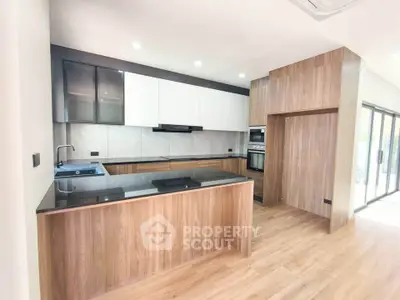 Modern kitchen with sleek wooden cabinetry and black countertops in open layout design.
