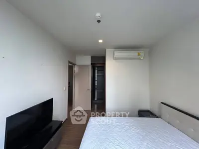 Spacious bedroom with modern furnishings and wall-mounted TV in a minimalist design.