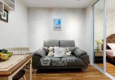 Cozy living room with modern sofa and dining area, adjacent to a stylish bedroom.