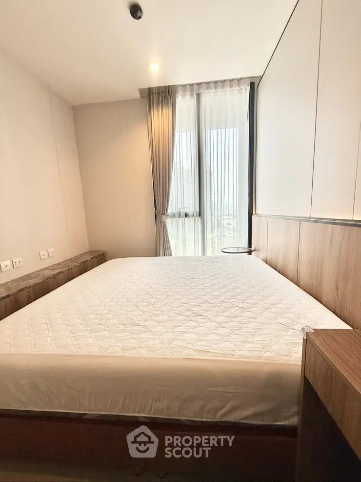 Modern bedroom with large window and elegant curtains in a stylish apartment.